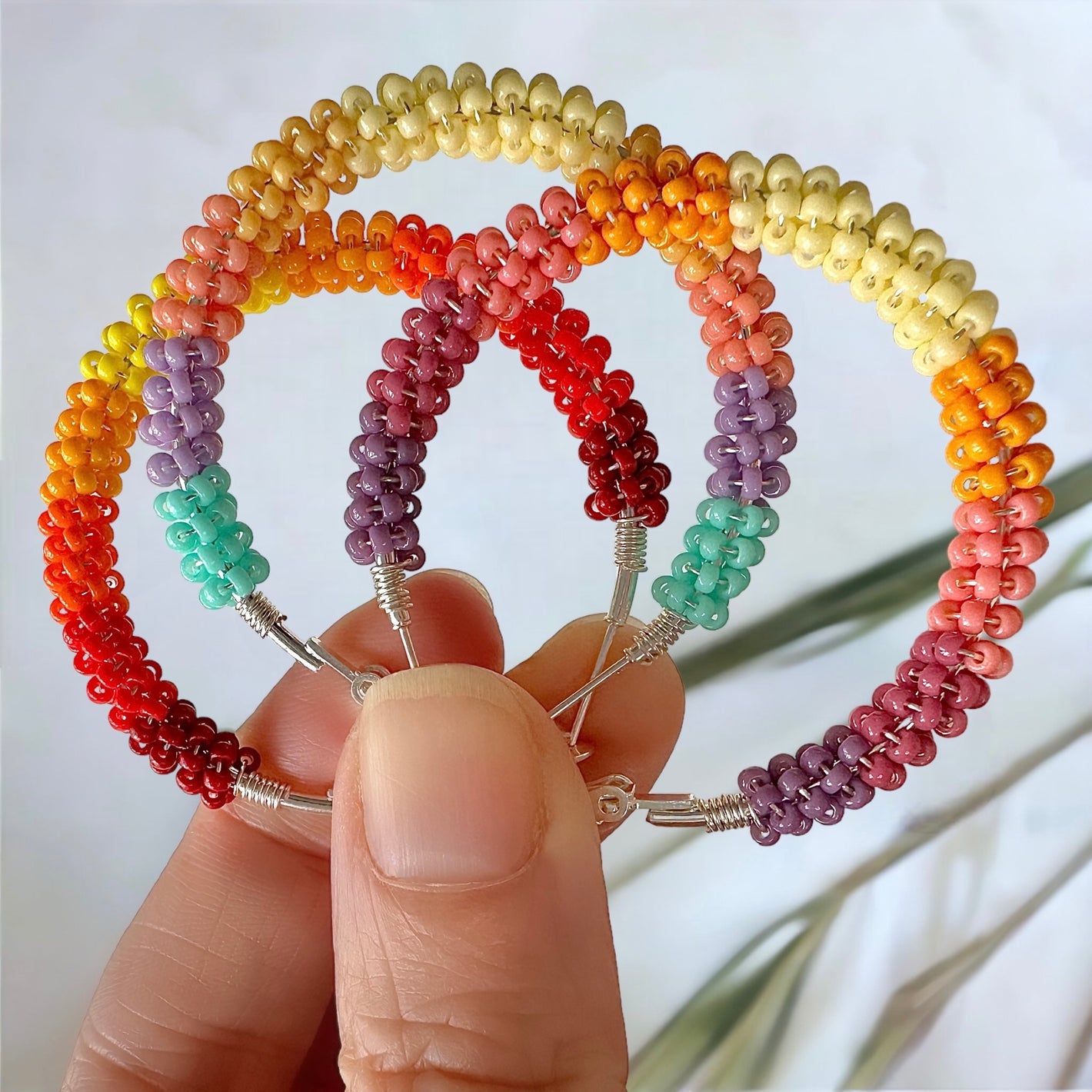Wire-wrapped beaded hoop earrings in sunset and sunrise patterns made with 11/0 Miyuki seed beads