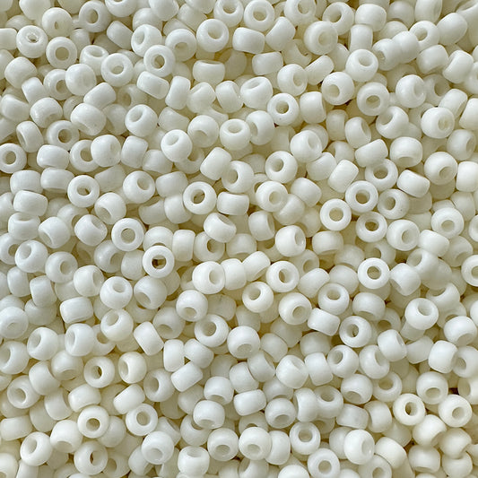 A close-up image of numerous small, white, cylindrical 11-2021: Matte Cream Miyuki 11/0 seed beads with central holes, densely packed together to fill the frame.