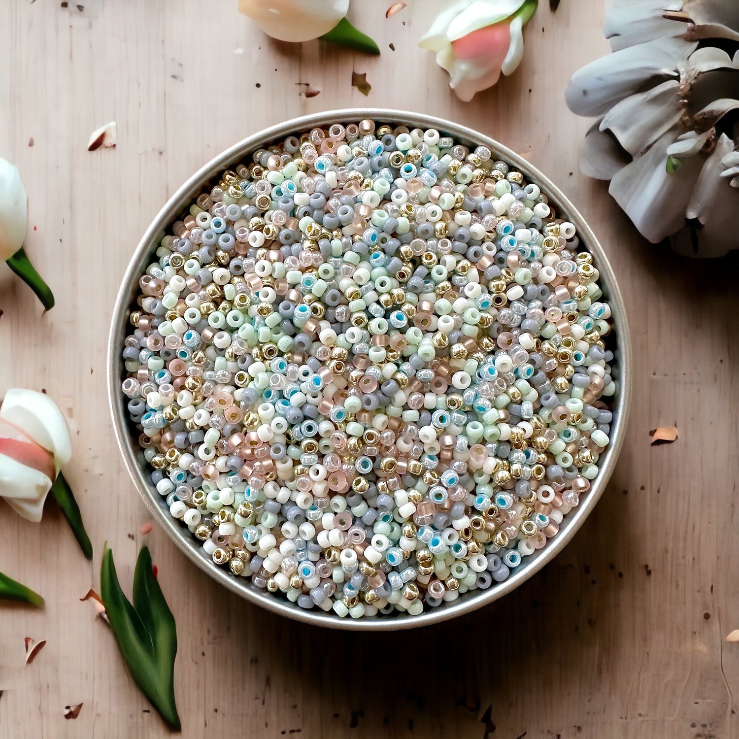 Mix of pastel colored 11/0 Miyuki seed beads in a silver tray on a wood surface