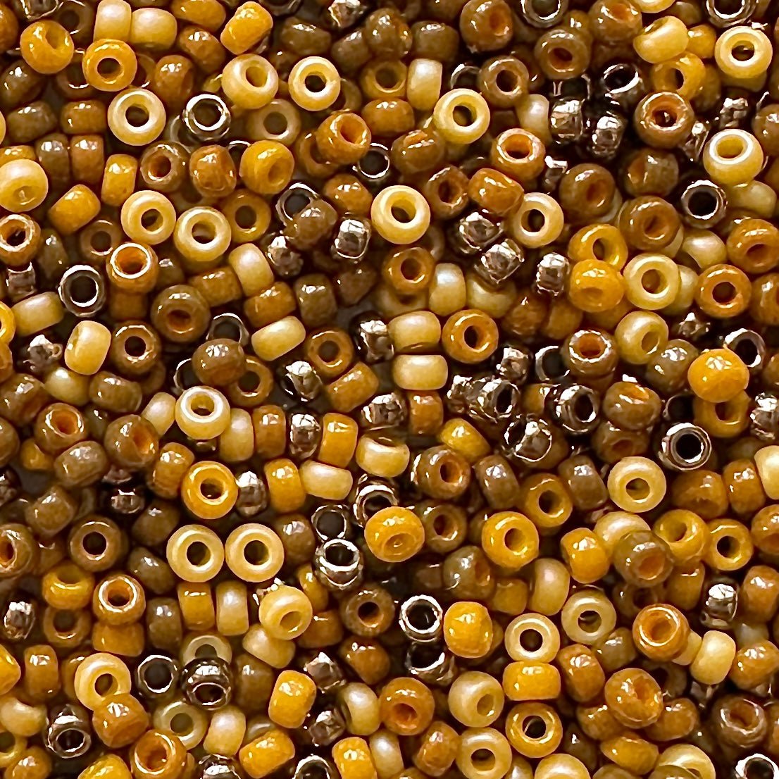 A mix of Miyuki round seed beads in shades of brown and golden yellow.