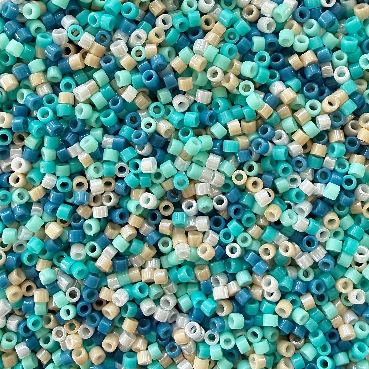 A mix of turquoise, teal, sandy beige, and white Miyuki seed beads.