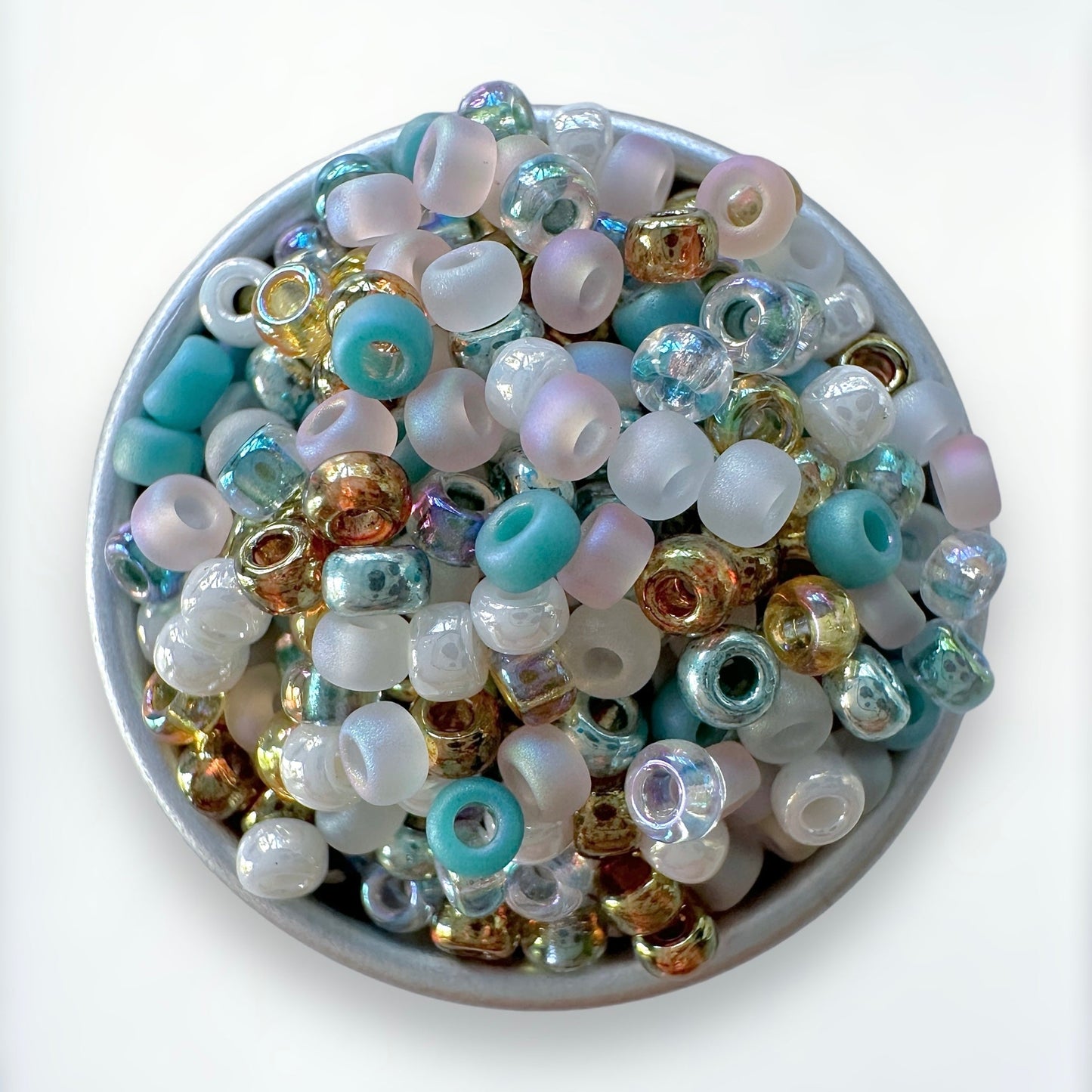 Mix of beach-inspired Miyuki 11/0 seed beads by The Bead Mix in a silver container with a white background