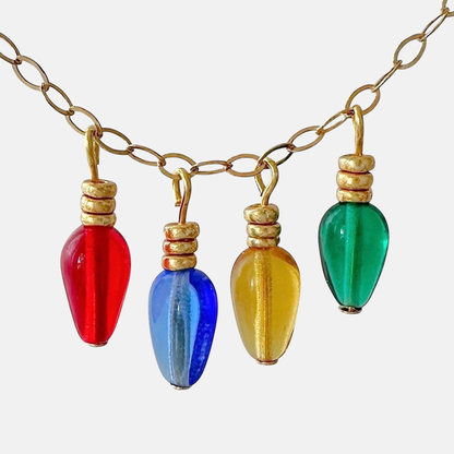 Charms made out of teardrop shaped beads with saucer beads to resemble vintage christmas light bulbs on a gold chain and white background.