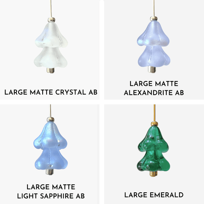 Four hanging beaded Christmas tree charms in white, purple, blue, and green arranged in a 4x4 grid on a light gray background.