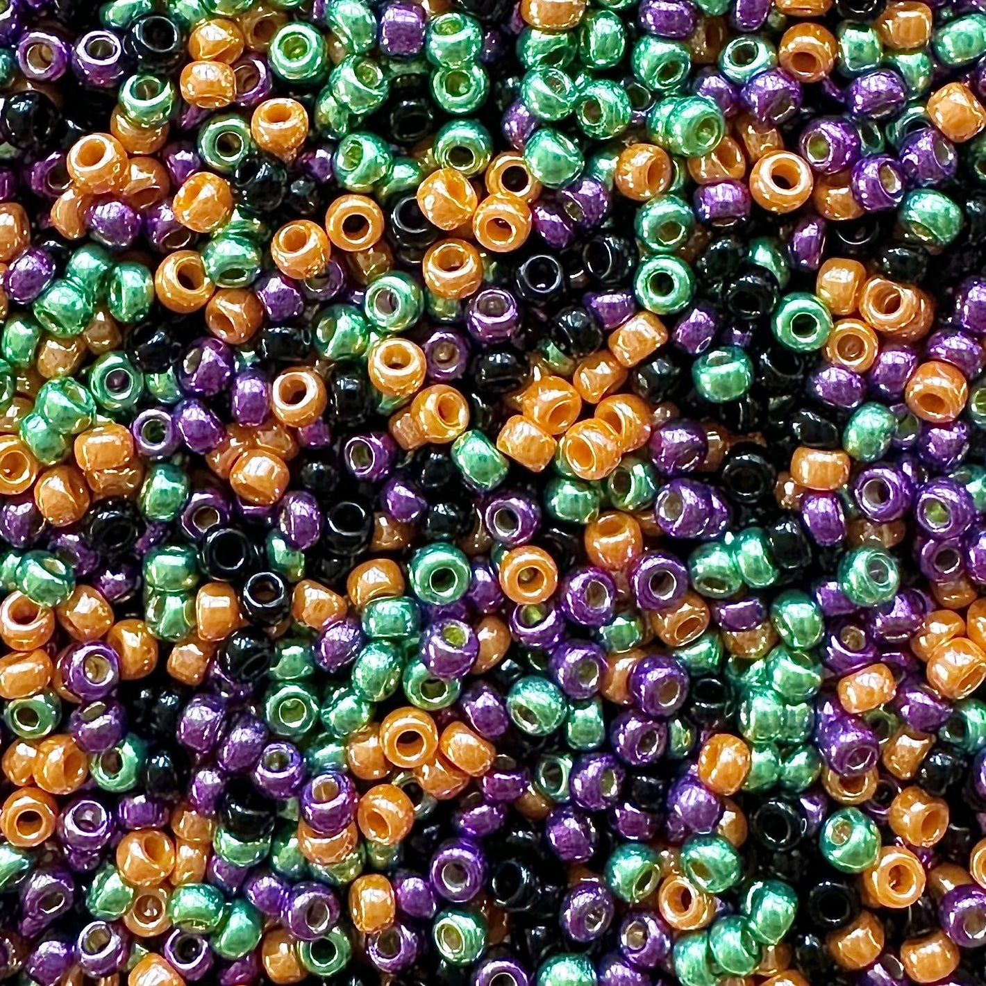 Mix of Miyuki seed beads in shades of purple, green, orange, and black.