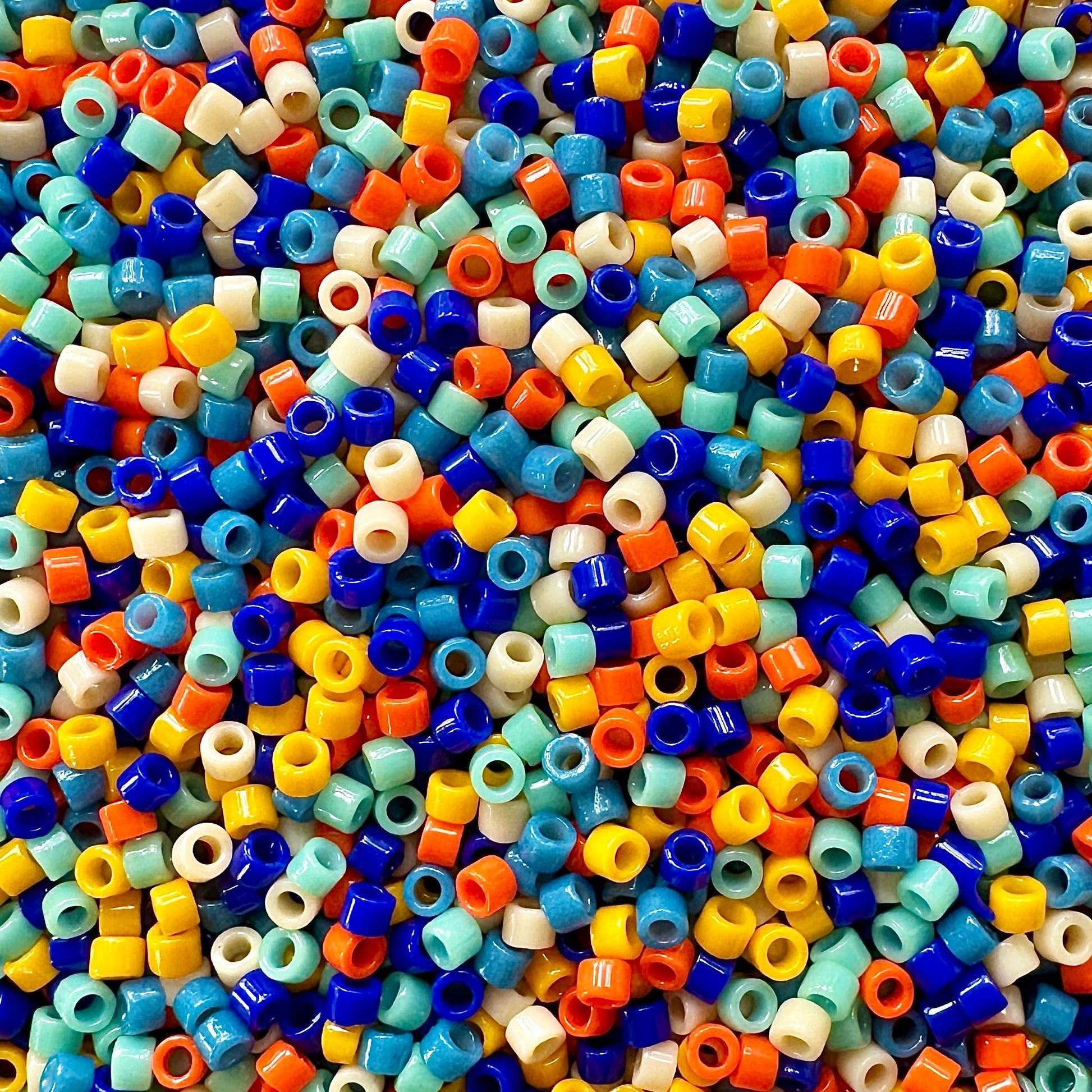 Mix of Miyuki Delica beads in shades of blue, turquoise, orange, and cream.