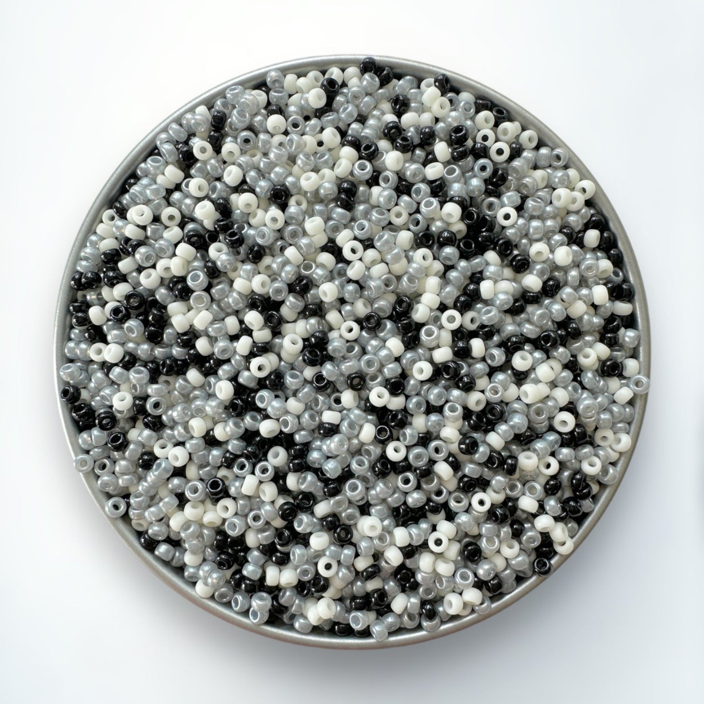 A mix of black, gray, and cream Miyuki 11/0 seed beads created by The Bead Mix in a silver container with a white background