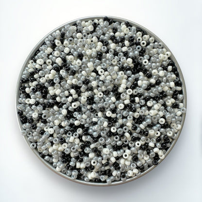 A mix of black, gray, and cream Miyuki 11/0 seed beads created by The Bead Mix in a silver container with a white background