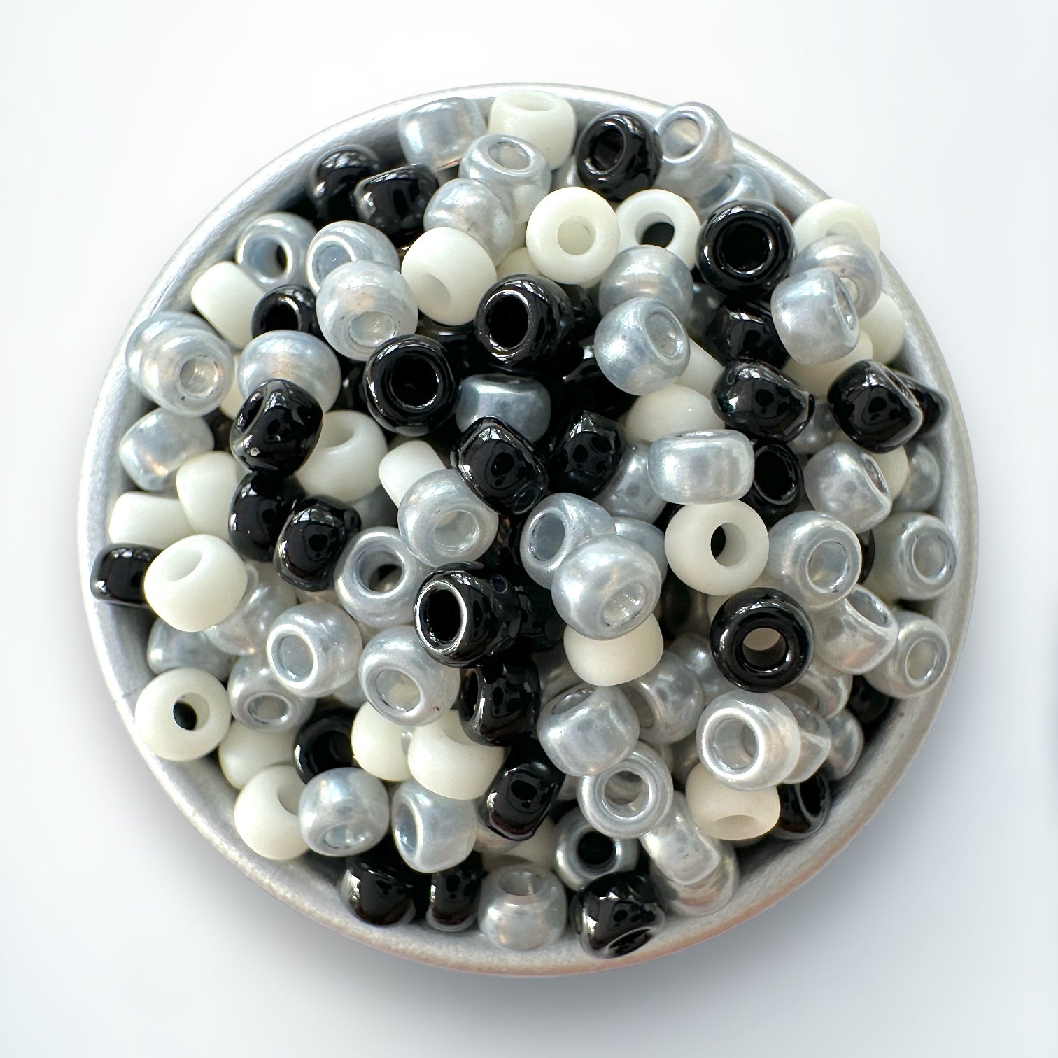 A mix of black, gray, and cream Miyuki 11/0 seed beads created by The Bead Mix in a silver container with a white background