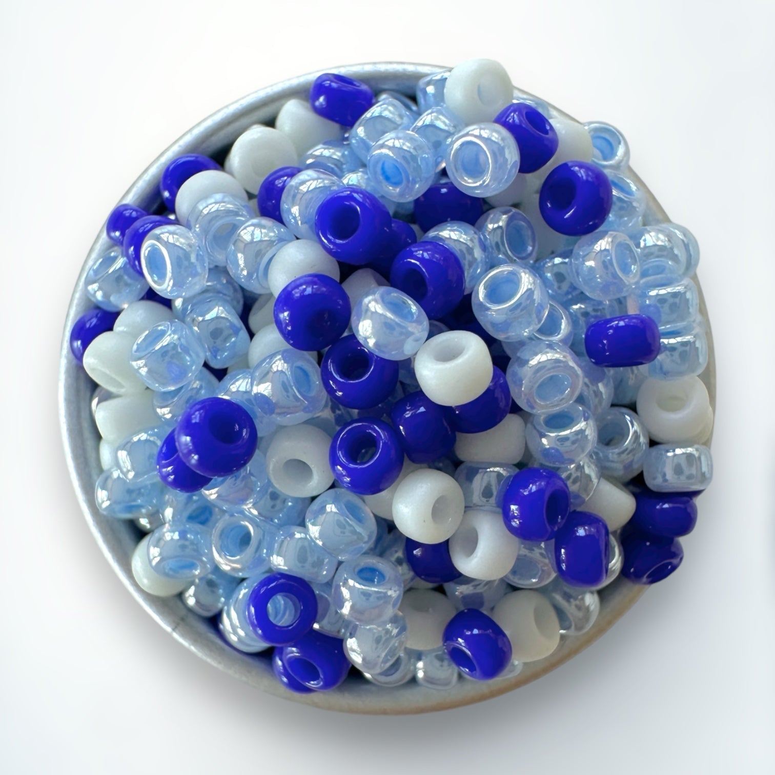 A mix of blue and cream Miyuki 11/0 seed beads created by The Bead Mix in a silver container with a white background