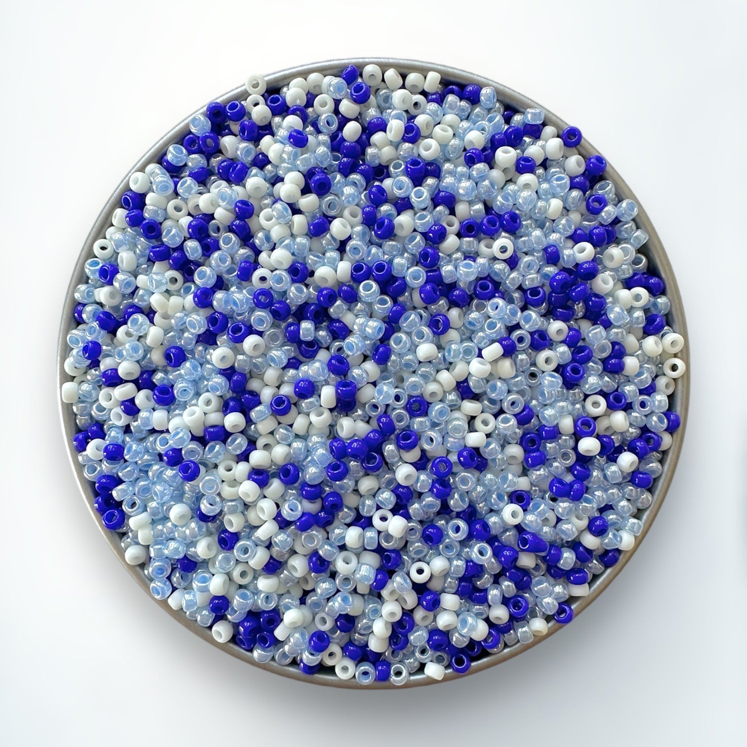 A mix of blue and cream Miyuki 11/0 seed beads created by The Bead Mix in a silver container with a white background