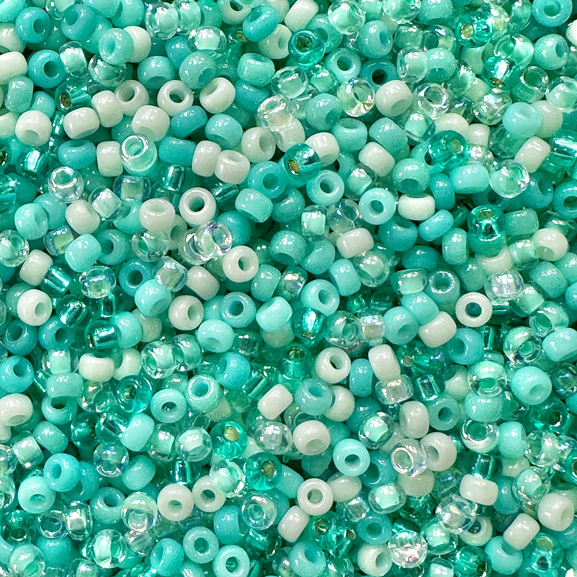 A mix of Miyuki round seed beads in shades of teal green, aqua, and mint green.