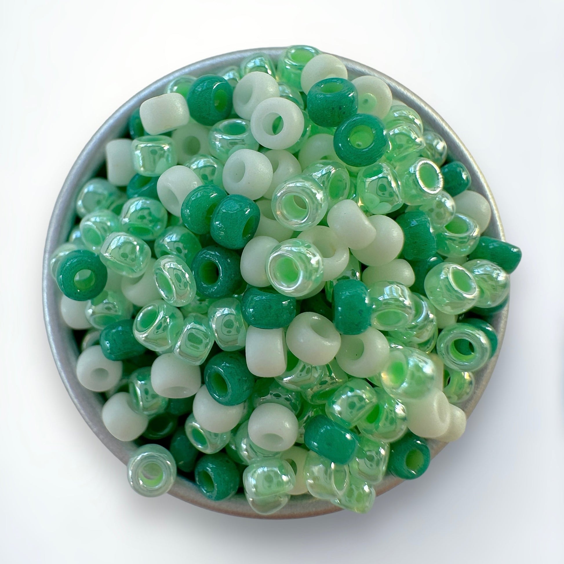 A mix of green and cream Miyuki 11/0 seed beads created by The Bead Mix in a silver container with a white background
