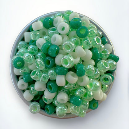 A mix of green and cream Miyuki 11/0 seed beads created by The Bead Mix in a silver container with a white background