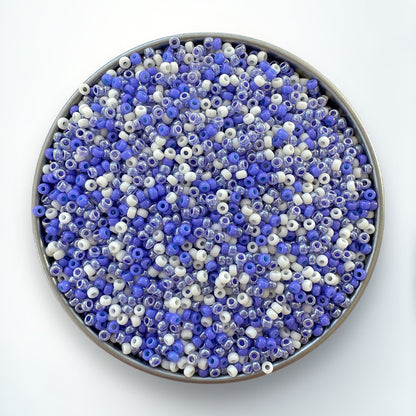 A mix of periwinkle and cream Miyuki 11/0 seed beads created by The Bead Mix in a silver container with a white background